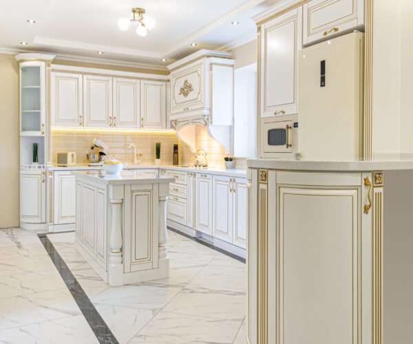 interior of neoclassical style white and gold wooden kitchen with island in luxury home
